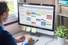 Person viewing laptop with calendar